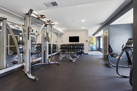A gym with a variety of equipment including treadmills, weights, and exercise machines.