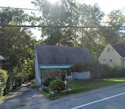 A house with a blue awning is surrounded by greenery.
