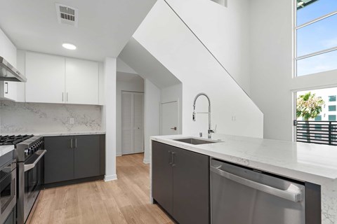 A modern kitchen with a stainless steel dishwasher and a white countertop.