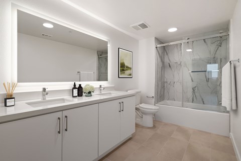 A modern bathroom with a large mirror, a sink, a toilet, and a bathtub.