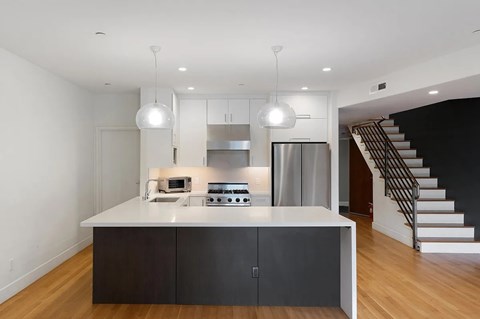 A modern kitchen with a white island and stainless steel appliances.