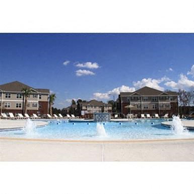 a large pool with water fountains in front of some buildings