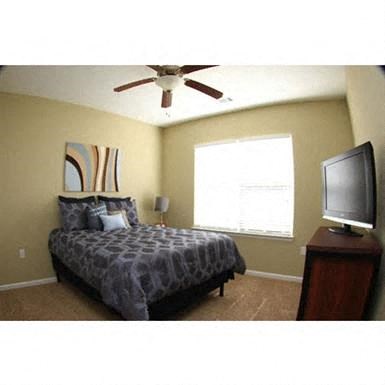 a bedroom with a bed and a ceiling fan and a tv