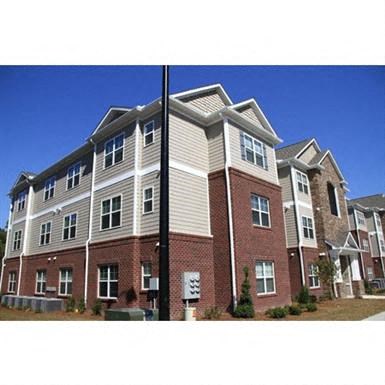 the front of a brick apartment building with white siding