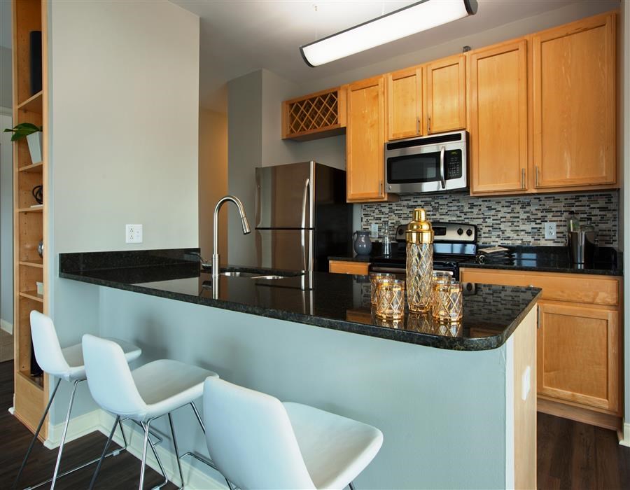 a kitchen with a counter with chairs and a sink