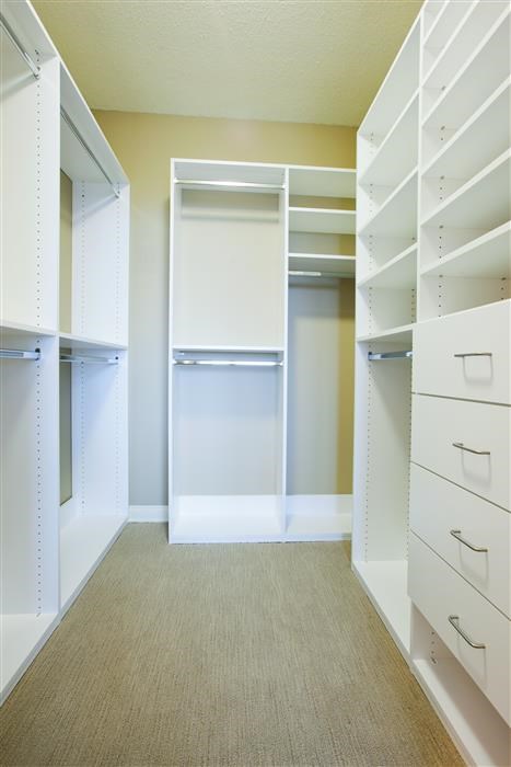 a walk in closet with white shelves and