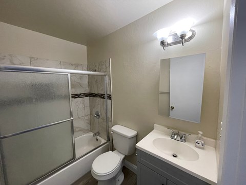 A bathroom with a toilet, sink, and shower.