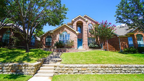 A house with a blue door and windows surrounded by a green lawn.
