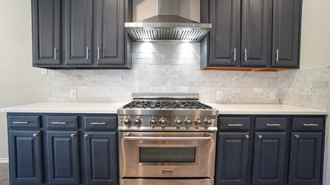 A kitchen with a stove top oven and blue cabinets.