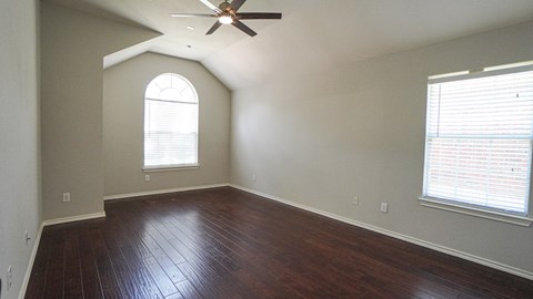 A room with a ceiling fan and a window with blinds.