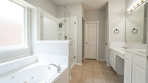 A white bathroom with a tub, sink, and mirror.