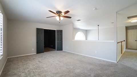 A room with a ceiling fan and carpeted floor.