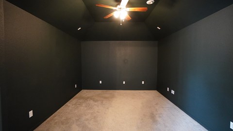 A room with a ceiling fan and carpeted floor.