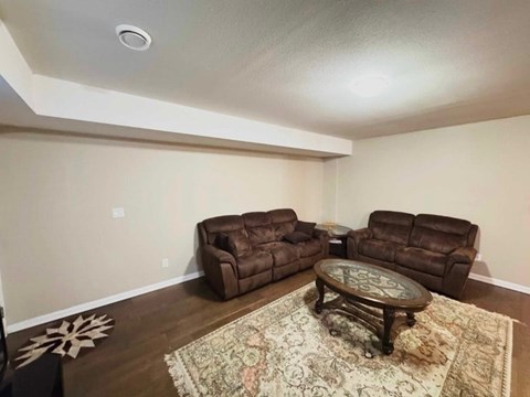 A living room with a brown leather couch and a glass coffee table.