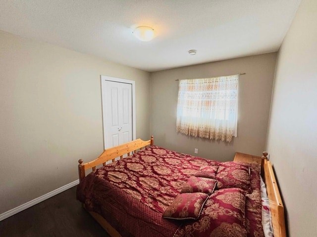 A bedroom with a bed, pillow, and a window with a curtain.