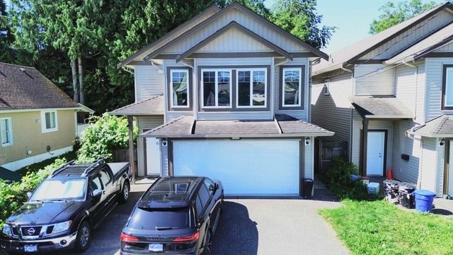 A house with a black truck and suv parked in front.