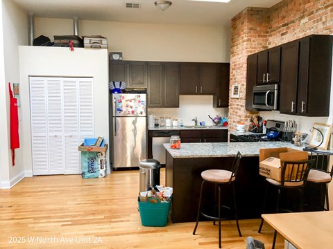 a kitchen with a refrigerator and a counter with chairs