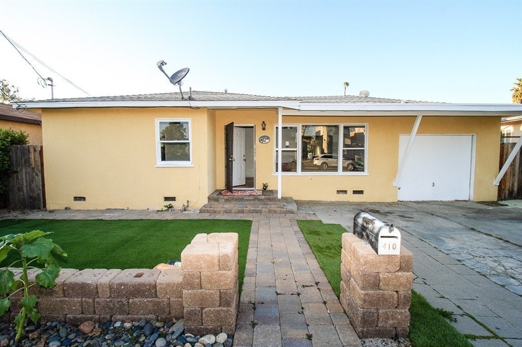 A yellow house with a grey roof and a white door.