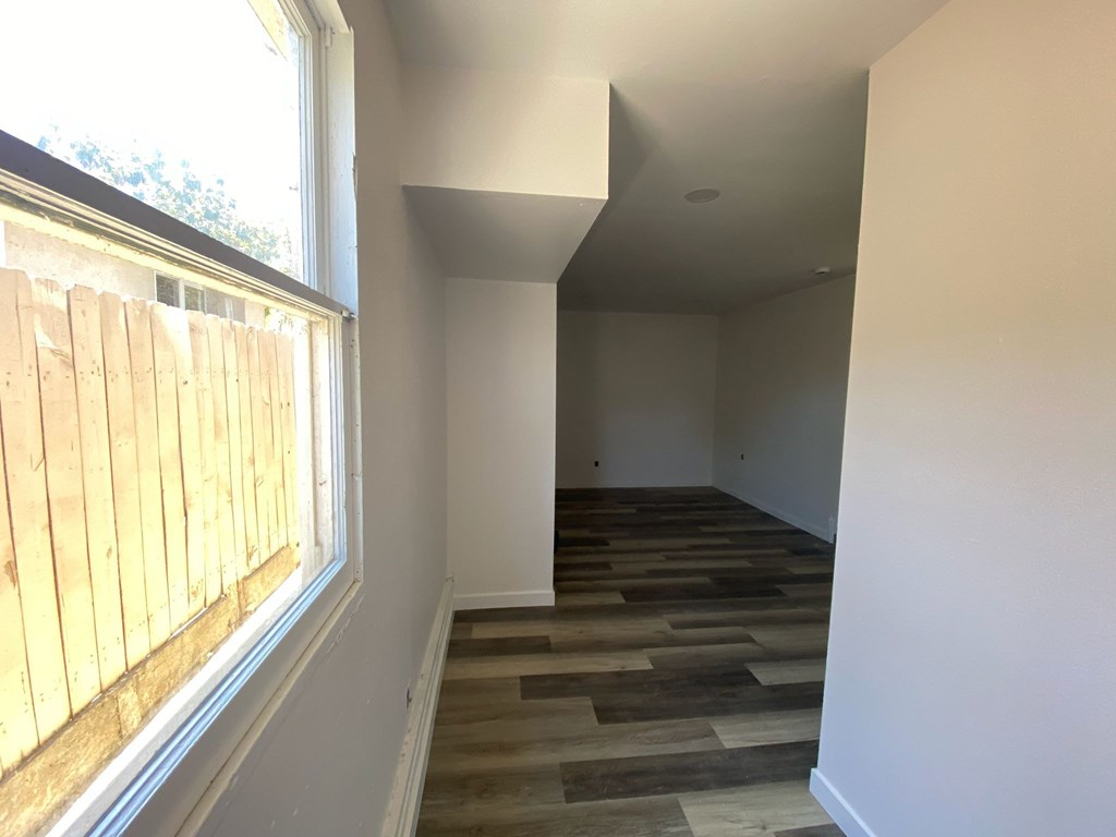 A room with wooden flooring and a window covered with wooden blinds.