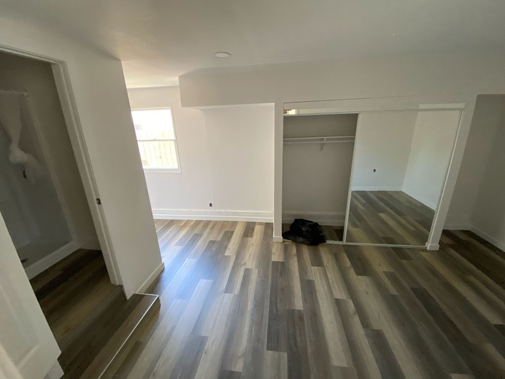 A room with wooden flooring and white walls.