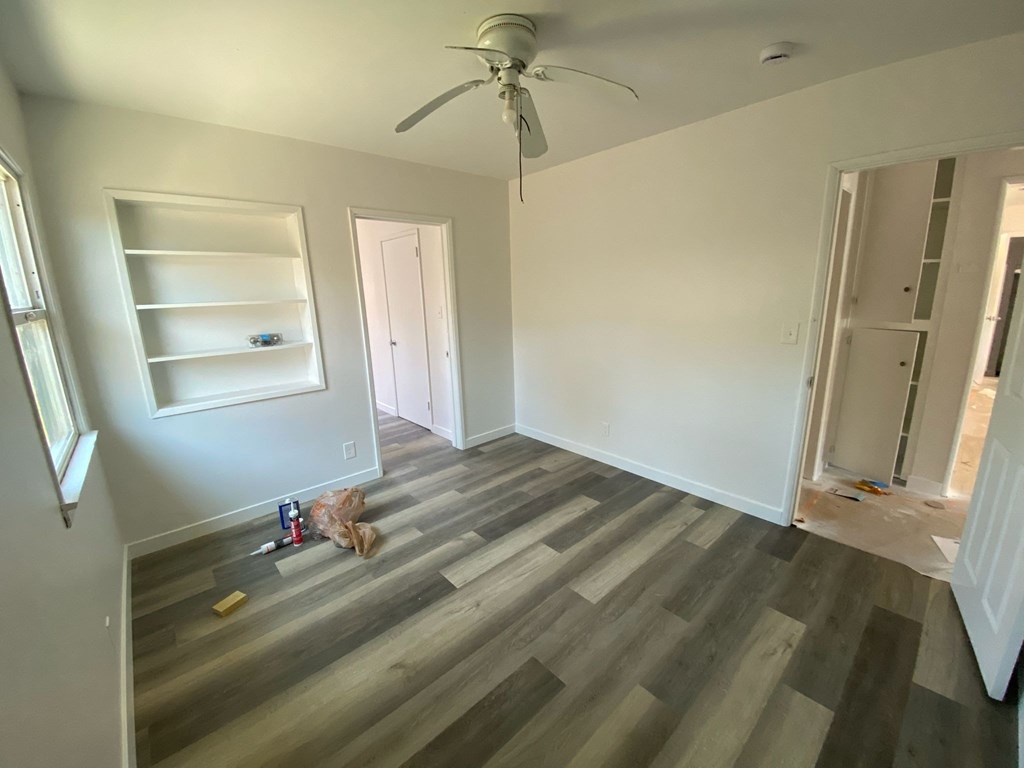 A room with a ceiling fan and a shelf is being renovated.