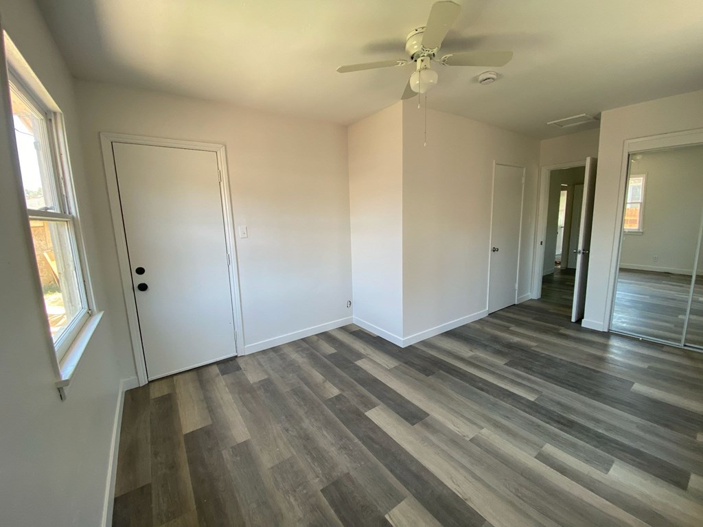A room with a ceiling fan and wood flooring.