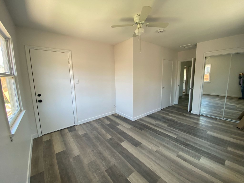 A room with a ceiling fan and wood flooring.