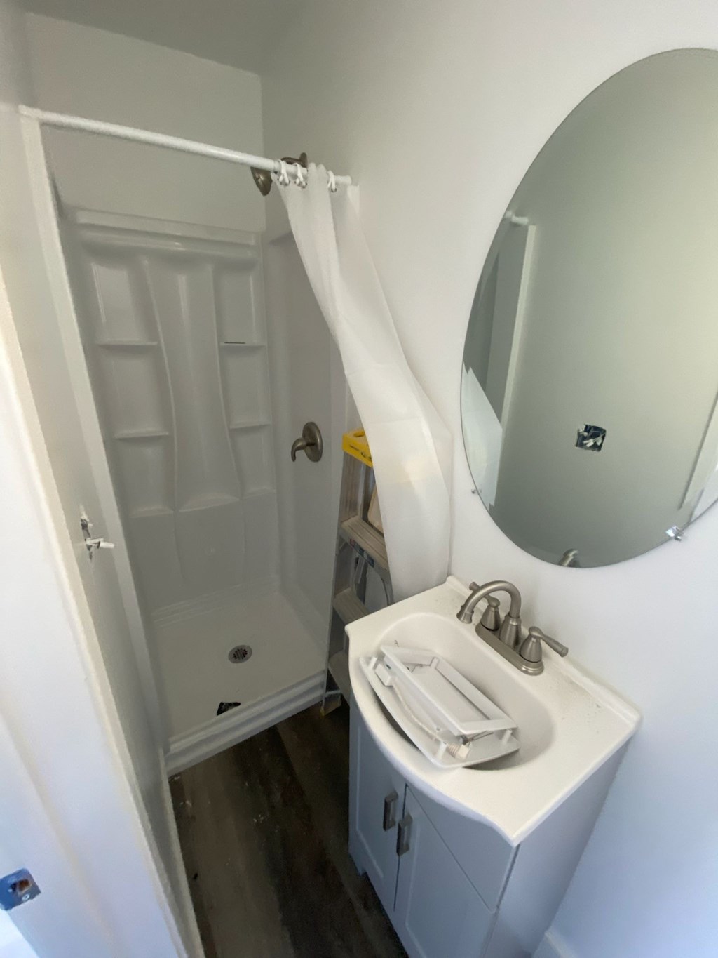 A white bathroom with a sink, mirror and shower.