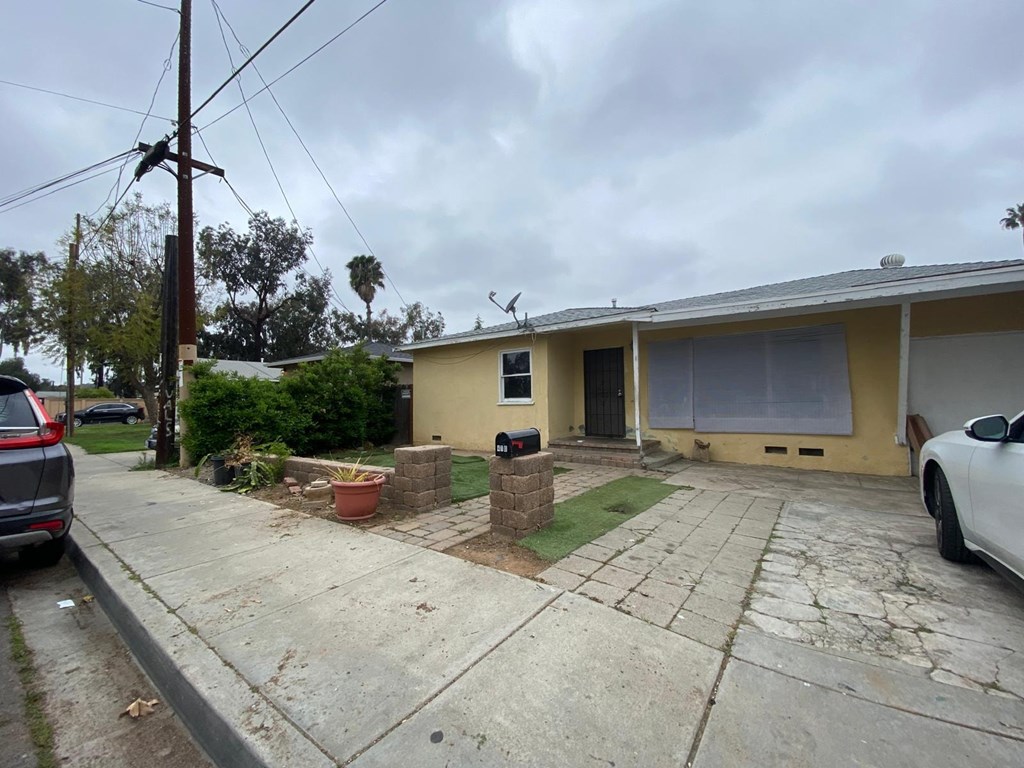 A house with a yellow exterior and a white car parked in front.