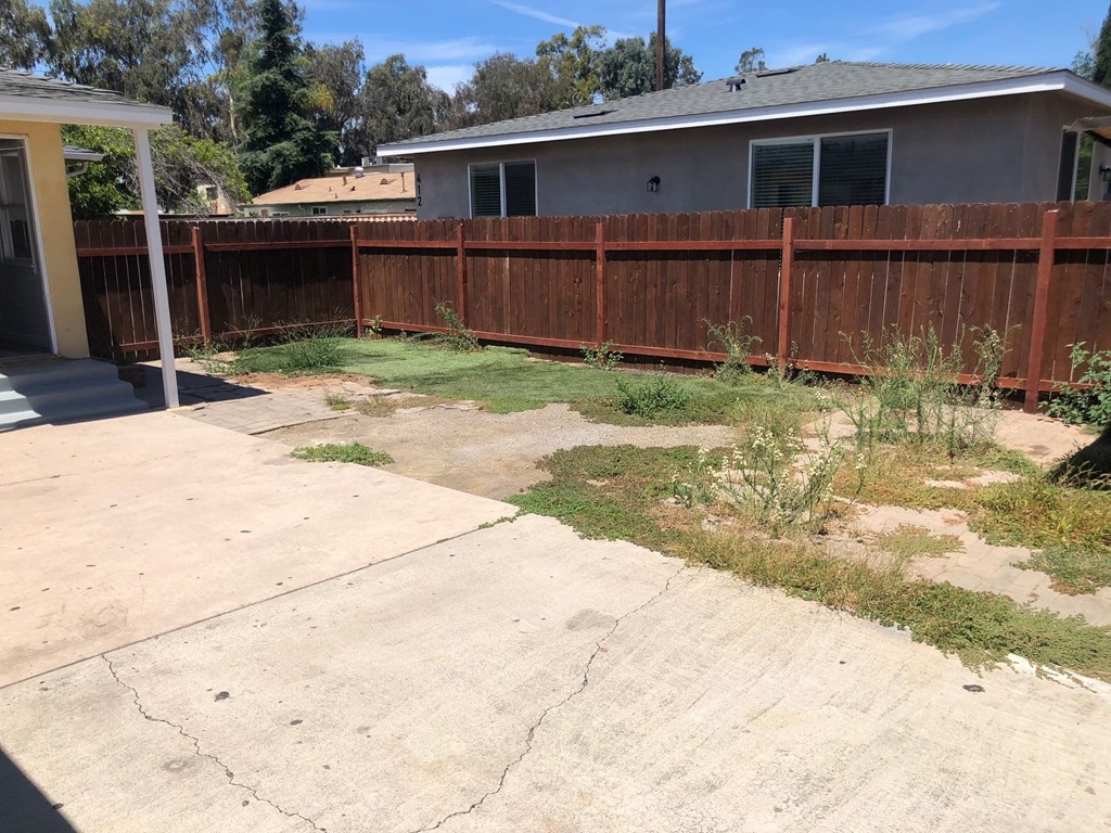 A backyard with a brown fence and a concrete patio.