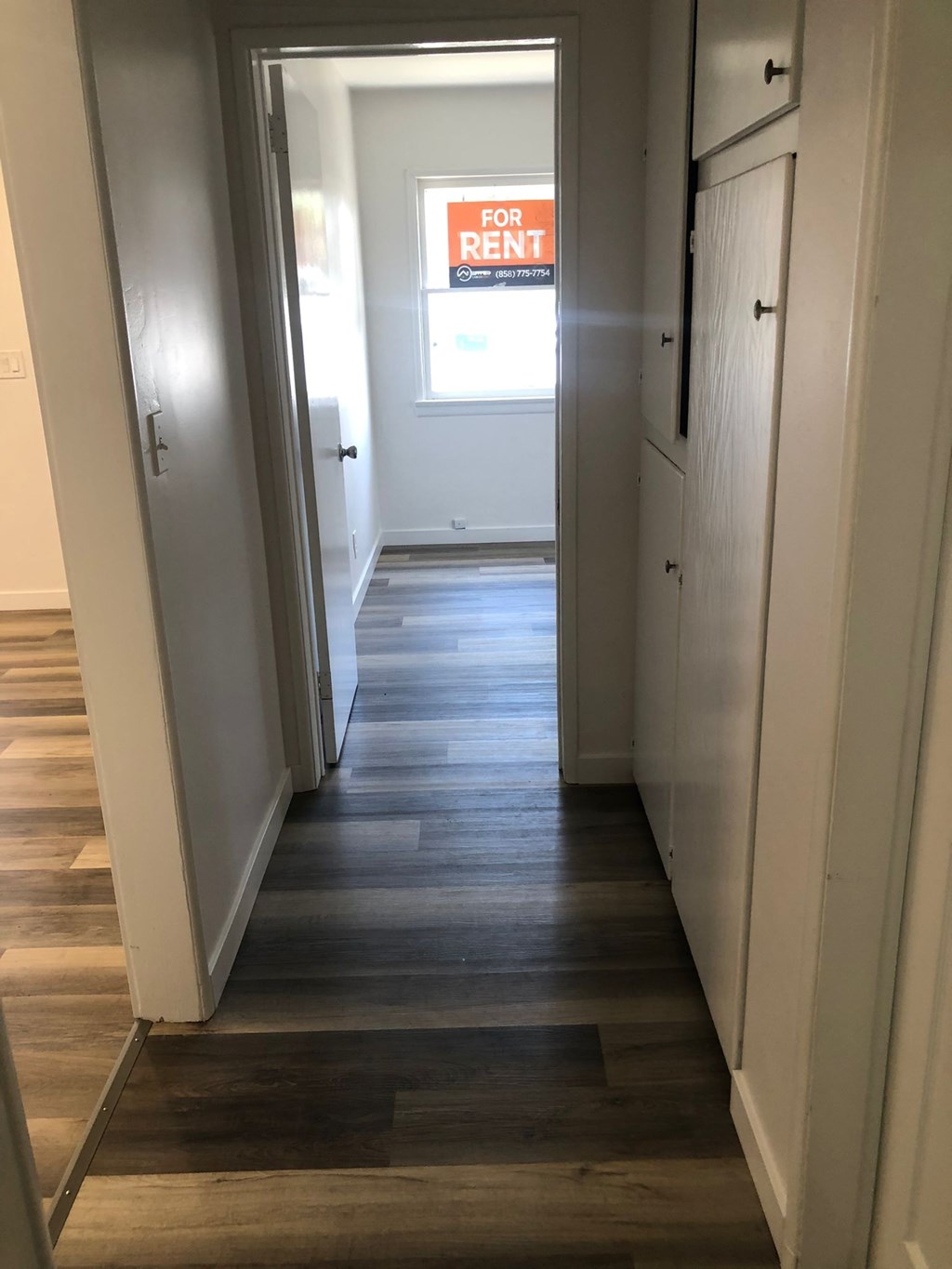 A hallway with a for rent sign in the distance.