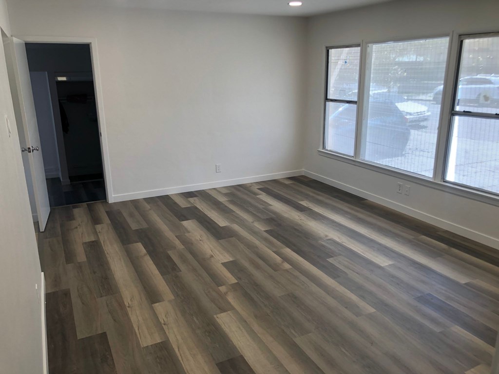 A room with wooden flooring and a window overlooking a street.
