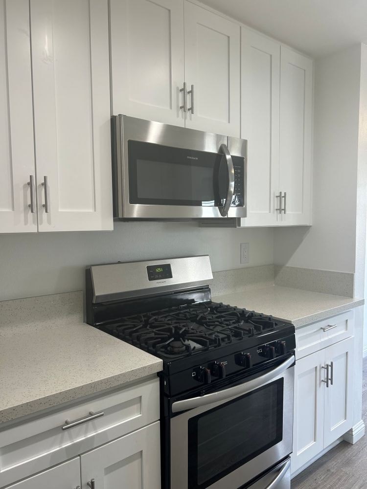 A kitchen with a stove and microwave mounted on the wall.