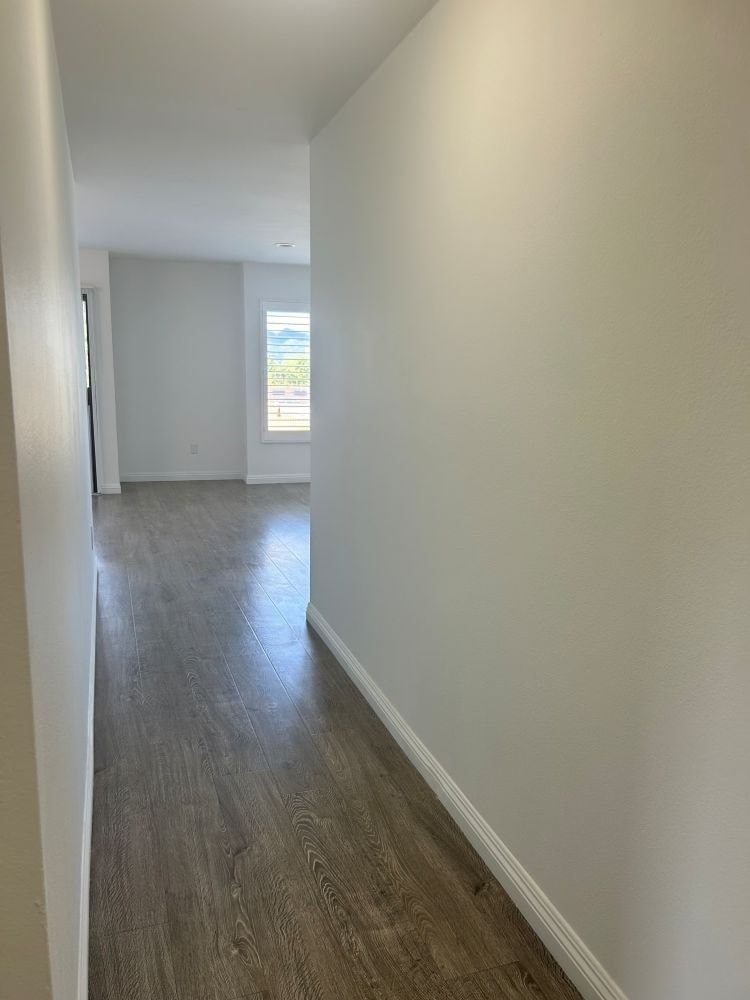 A long hallway with wood floors and white walls.
