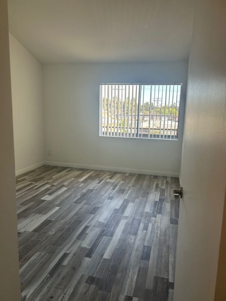 A room with a window and wooden flooring.