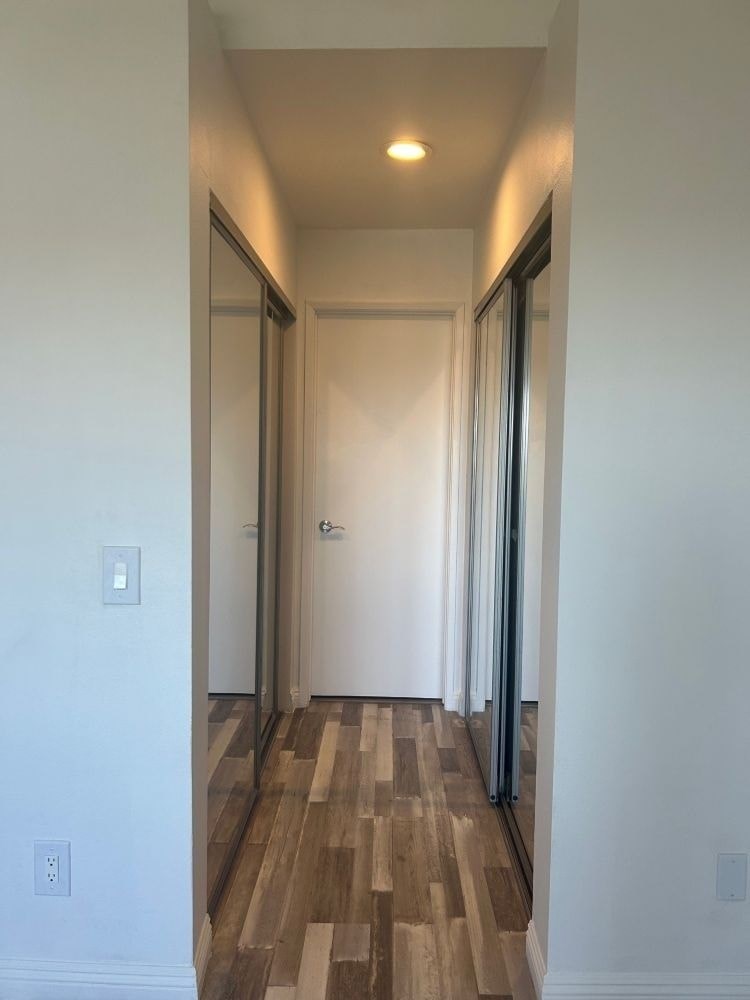 A hallway with a wooden floor and white walls.