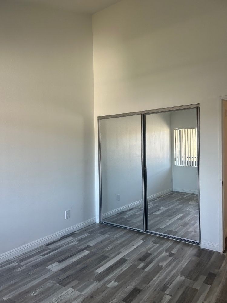 A room with a sliding glass door and wood flooring.