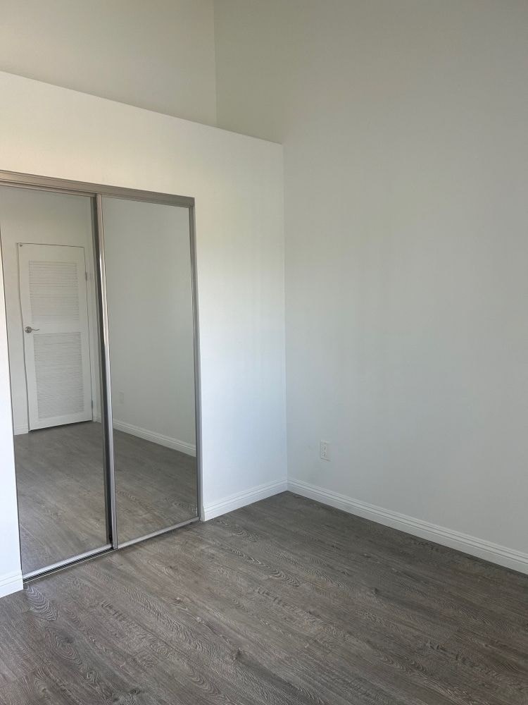 A room with a grey floor and a white wall with a mirrored door.