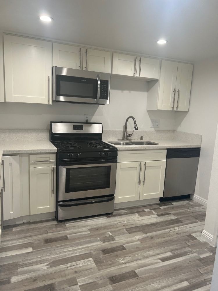 A kitchen with a black stove top oven and a black microwave above it.