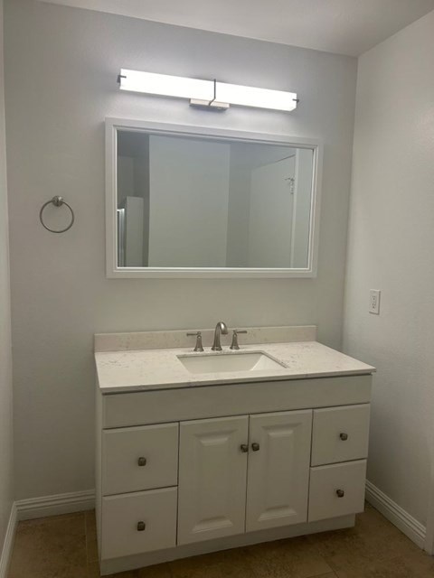 A bathroom with a white sink and a mirror above it.