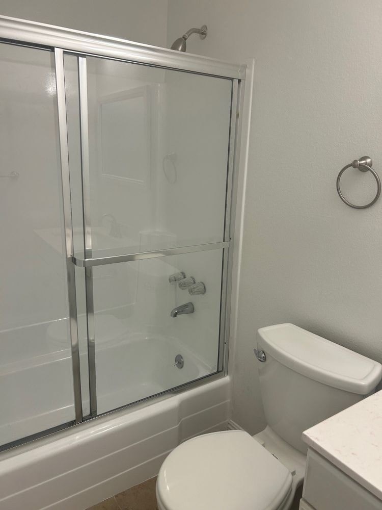 A white toilet sits next to a glass shower door in a bathroom.