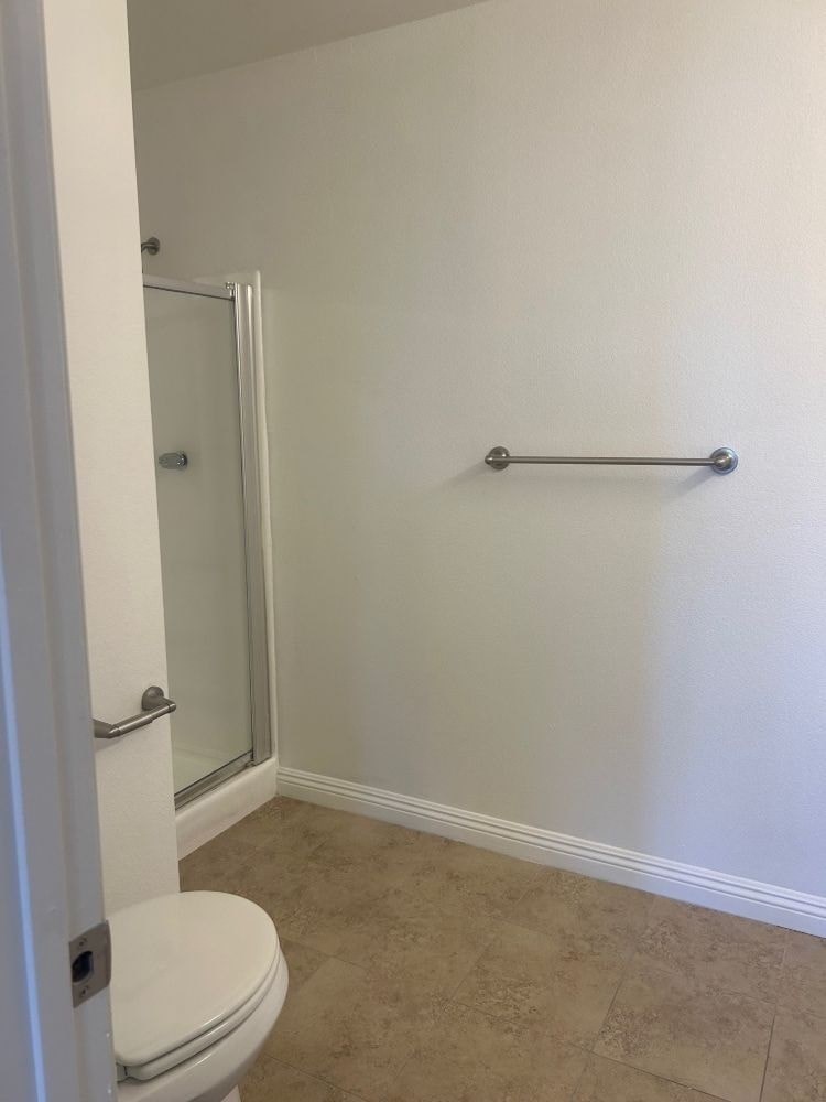 A white toilet in a small bathroom with a glass shower door.