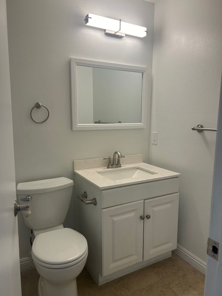 A white toilet and sink in a small bathroom.