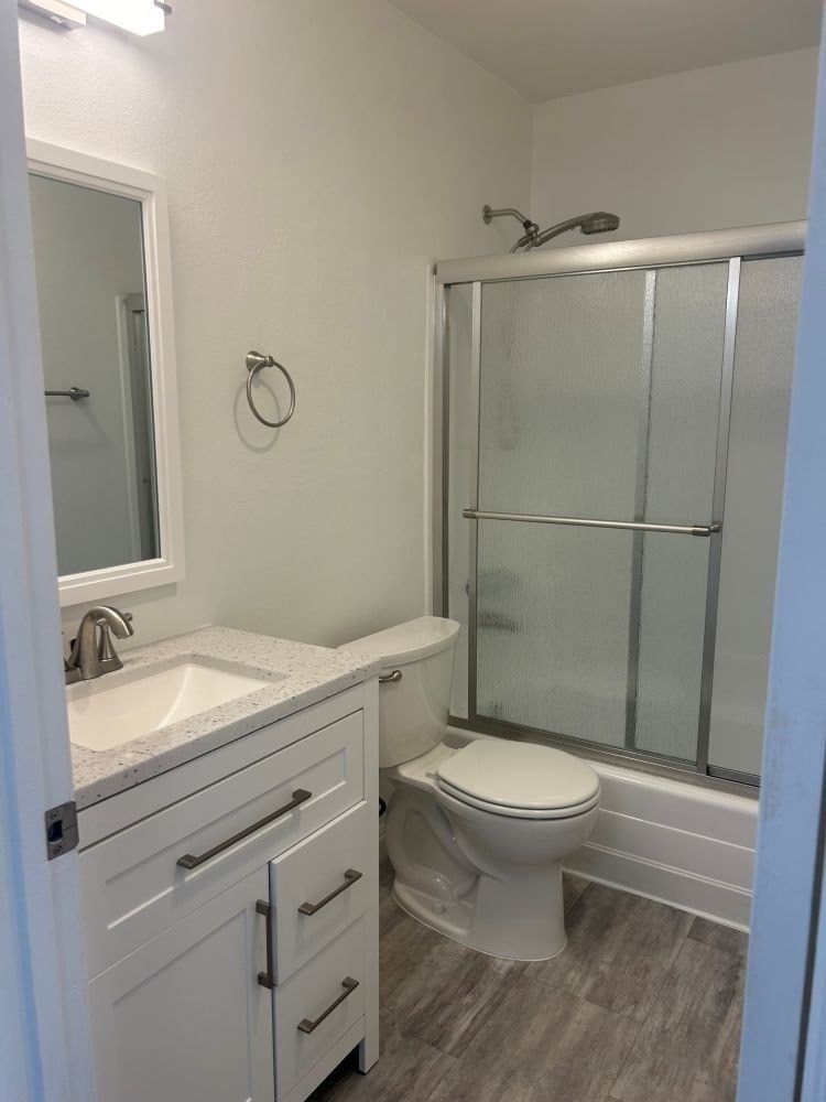 A white bathroom with a toilet, sink, and shower.