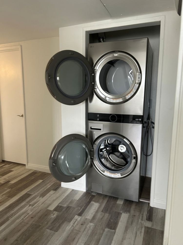 A washing machine with a dryer on top is in a white doorway.