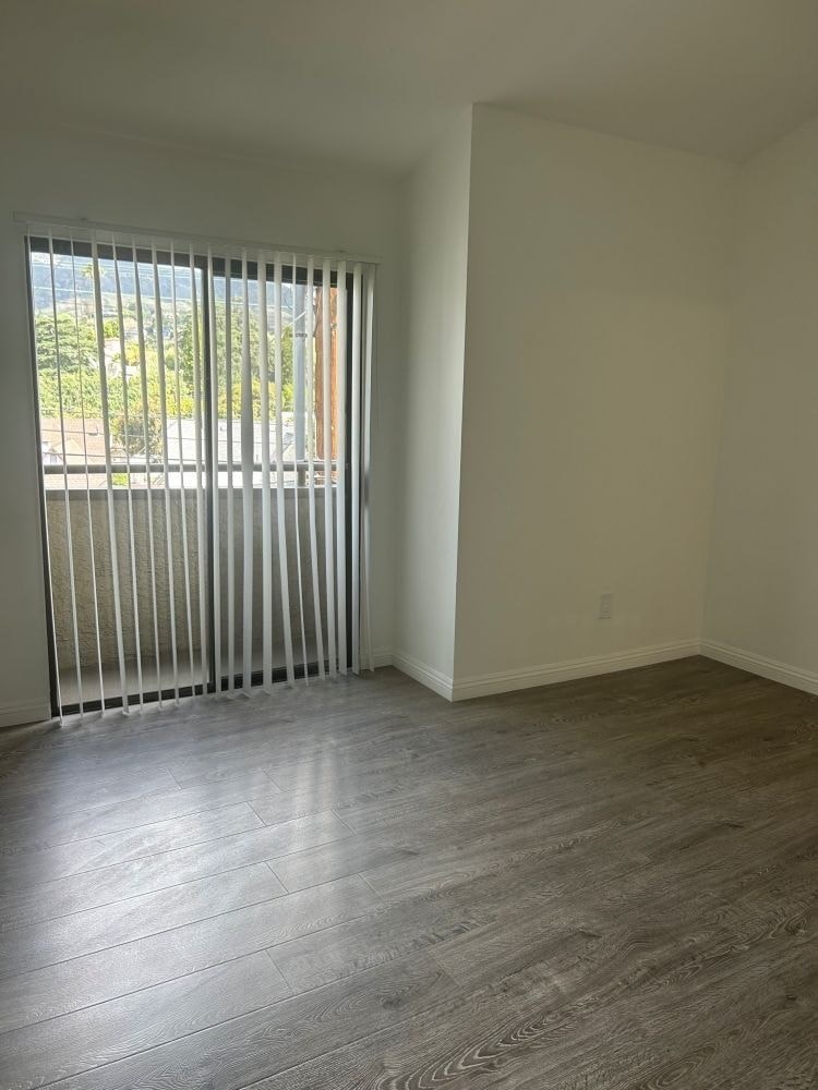 A room with a window covered by white blinds.
