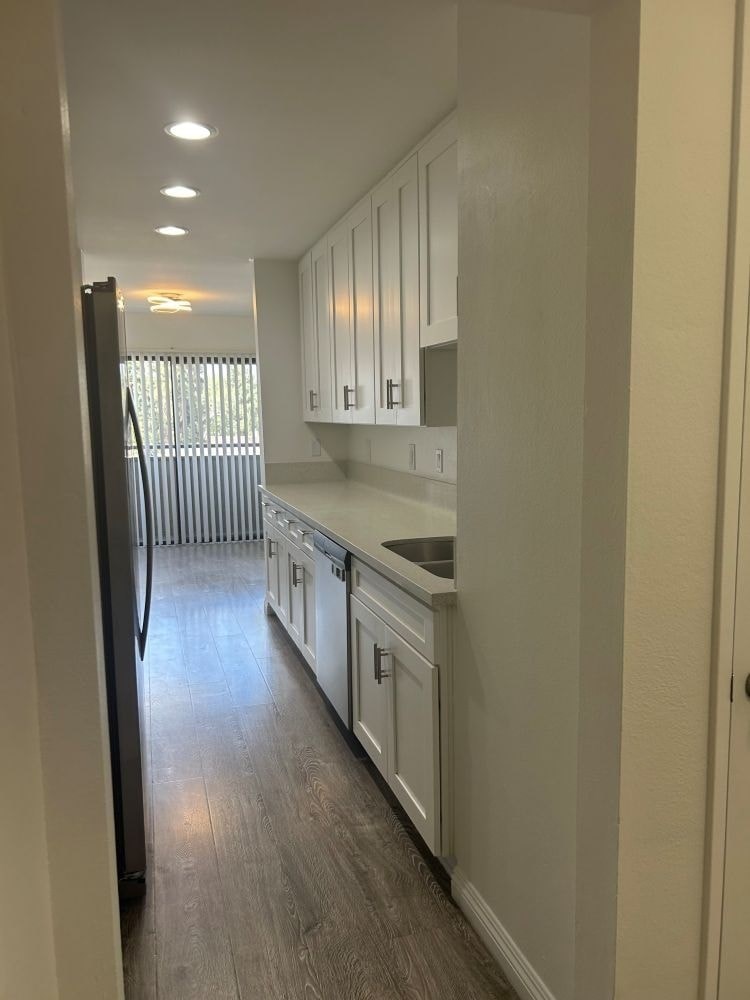 A kitchen with white cabinets and a black refrigerator.