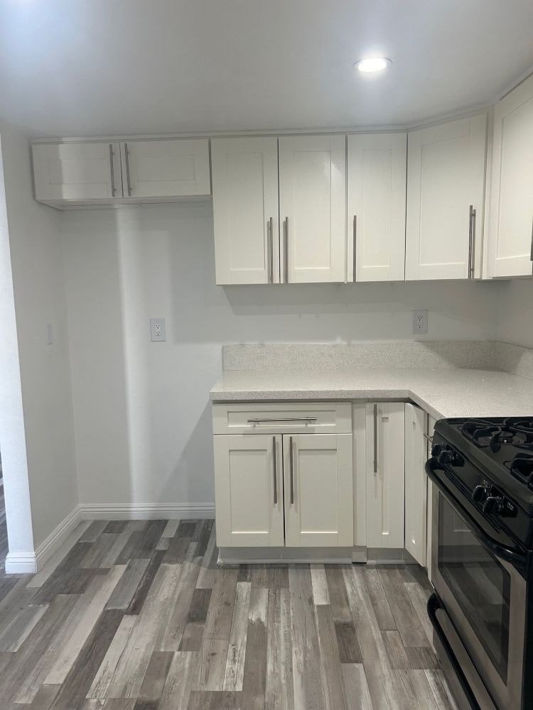 A kitchen with a black stove top oven and white cabinets.