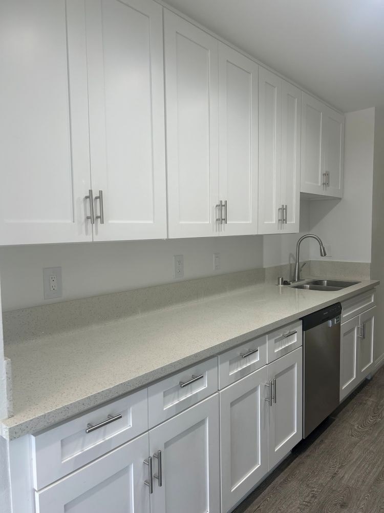 A kitchen with white cabinets and a sink.