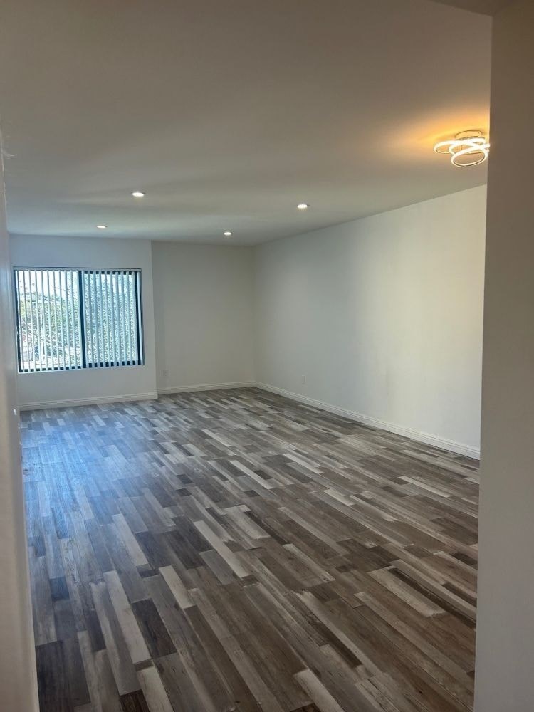 A room with wooden flooring and a window with blinds.